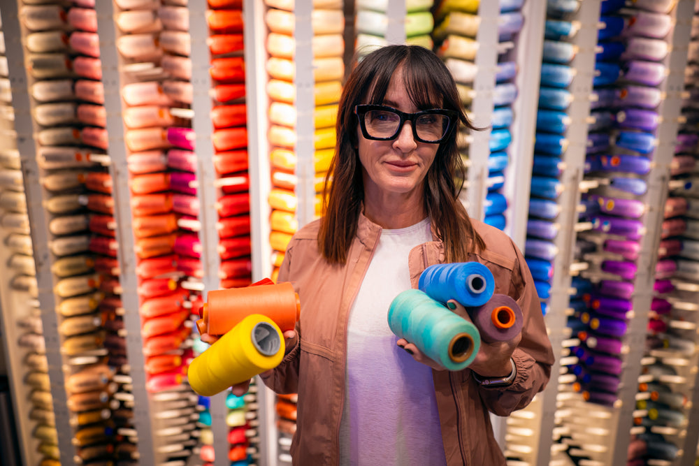 A textile maker holding colorful thread in a workshop