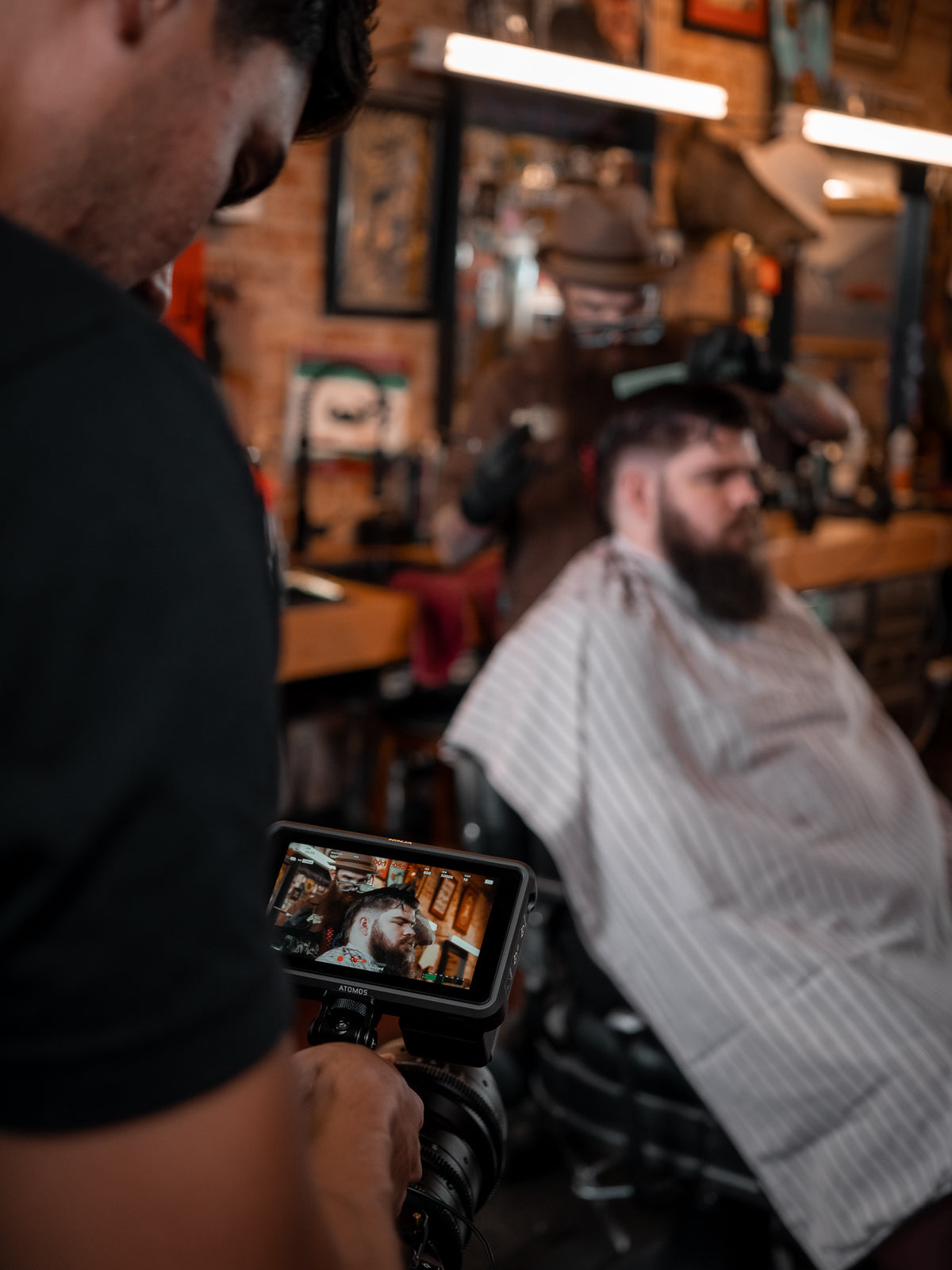 A camera operator capturing a barber at work in his shop