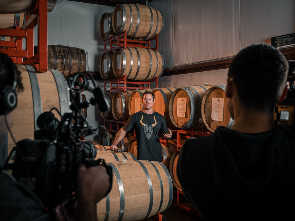 A Paragraphic crew member filming an interview among barrels at a meadery